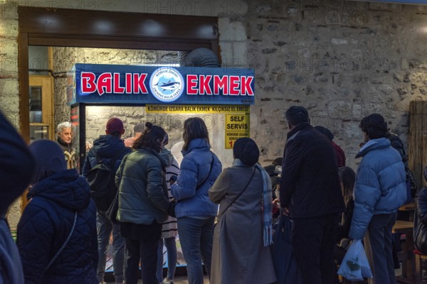 Istanbul, Turkey. January 3rd 2025. A queue of customers line up at a popular stall selling Balik Ekmek the well-known fish sandwich, popular street food in Istanbul, Turkey