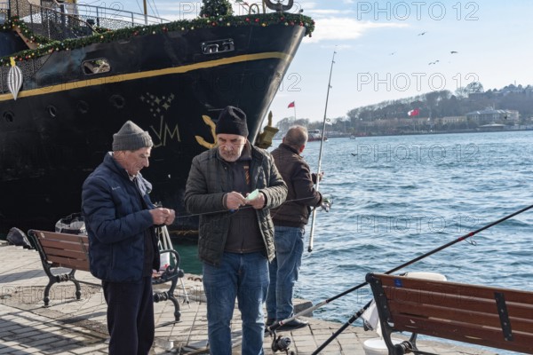 Istanbul, Turkey. January 3rd 2025. Turkish men fishing on the dock at Karakoy Port on the European Shore of the Bosporus Straight, Istanbul, Turkey