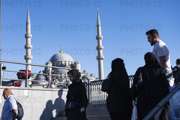 Istanbul, Turkey. September 18th 2025. A typical busy street scene in Istanbul with people passing the dome and minarets of Yeni Cami an iconic Istanbul mosque in the Fatih district of Istanbul, Turkey