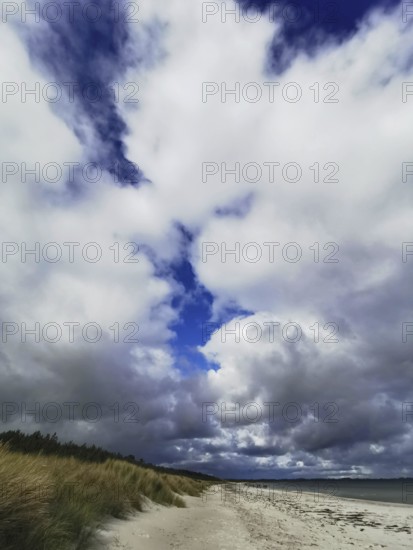 Dramatic sky with blazing clouds over a secluded beach with dunes, Rügen, Baltic Sea