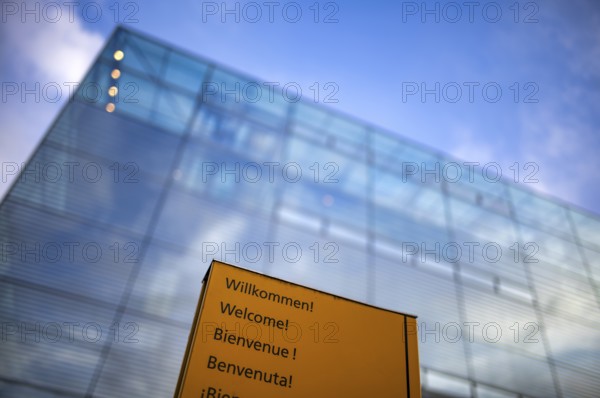 Sign, welcome sign with the words Willikommen Welcome Bienvenue Benvenuta in front of art museum, Cube, Glaskubus, Stuttgart, Baden-Württemberg, Germany