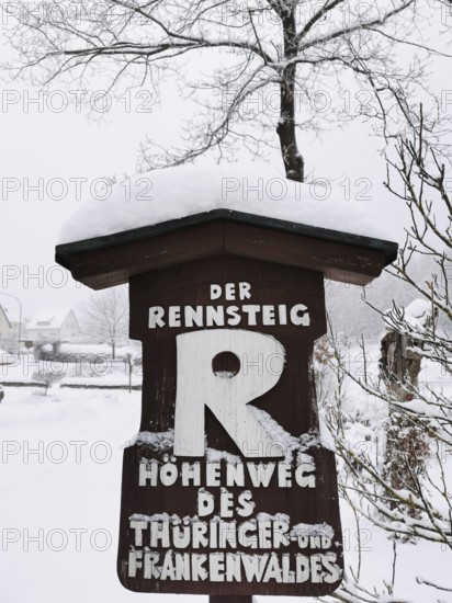 Snowy sign of the Rennsteig in wintry rural surroundings, hiking in the Franconian Forest nature park Park