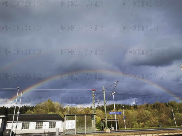Double rainbow over a small train station area under a cloudy sky, Steinbach am Wald, Rennsteig, Frankenwald nature park Park