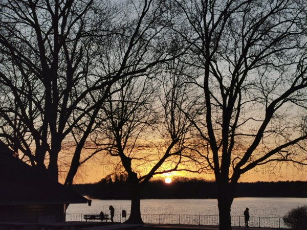 People walk along the Müggelsee waterfront at sunset, Berlin