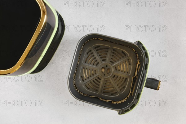 Top view of modern air fryer with empty basket lined with parchment paper, ready for quick healthy cooking in a contemporary home kitchen