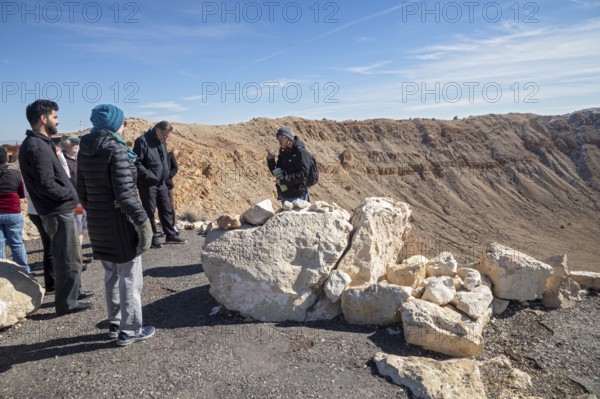 Winslow, Arizona - Meteor Crater. The crater was formed about 50, 000 years ago. It is 560 feet deep and abouat three-quarters of a mile in diameter. It is now a major tourist attraction. A tour guide talks with visitors on the crater's rim