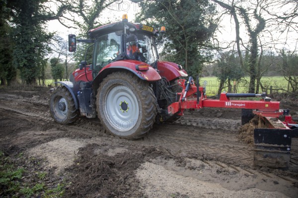 Tractor grading and levelling work repair a muddy, flood-prone country lane, Sutton, Suffolk Sandlings, Suffolk, England, UK