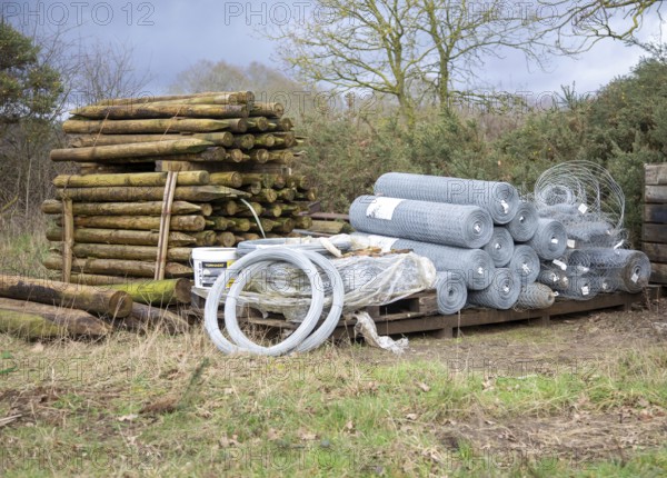 Agricultural fencing supplies wooden fence posts, rolls of wire stacked outdoors post-and-wire fencing system, UK