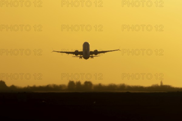 Airbus commercial passenger airliner jet aircraft taking off in flight silhouette at sunset at London Stansted airport, Essex, England, United Kingdom