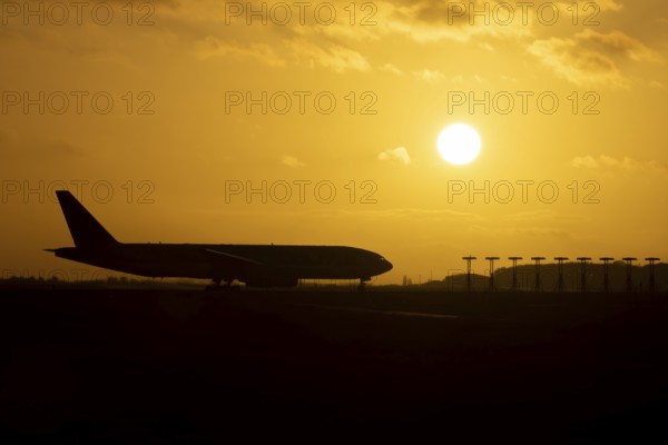 Boeing 777 A7-BFL commercial jet aircraft of Qatar cargo waiting to take off silhouette at sunset at London Stansted airport, Essex, England, United Kingdom