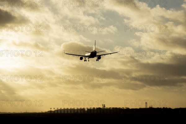 Boeing 737 commercial passenger airliner jet aircraft flying on approach to land over runway lights at sunset at London Stansted airport, Essex, England, United Kingdom