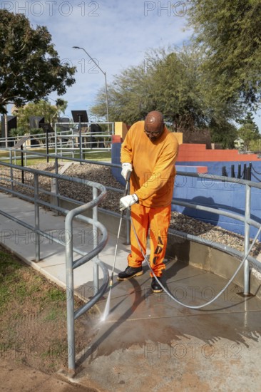 Phoenix, Arizona - A prisoner cleans a sidewalk in Wesley Bolin Memorial Plaza, a public park next to the Arizona State Capitol complex. The Arizona Department of Corrections puts thousands of prisoners to work every day on a variety of projects