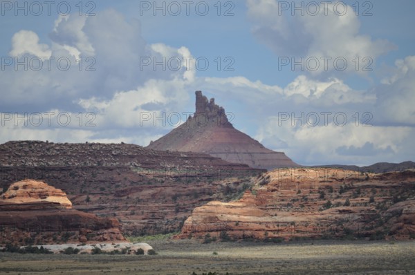 Distinctive pointed rock rises high, surrounded by red rocks and dramatic cloud formations, Canyonlands National Park, Utah, USA