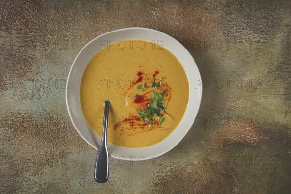 Pumpkin cream soup, in a white bowl on a textured background, top view, homemade, no people, rustic style