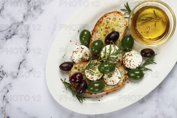 A plate with a snack, ciabatta bread with cheese and olives, olive oil, spices and herbs, top view, no people