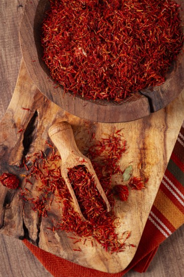 Spice saffron threads, in a wooden bowl, on a wooden table, top view, close-up