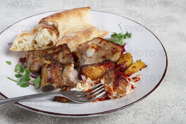 A plate with leftover pork kebab, with bread, on a white plate, close-up, there are no people