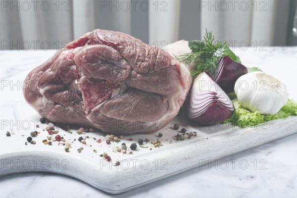 Raw pork knuckle, on a wooden chopping board, with spices, close-up, top view, no people