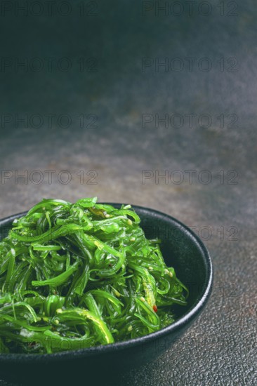 Chuka salad, made from fresh seaweed, with sesame dressing, served in a black bowl