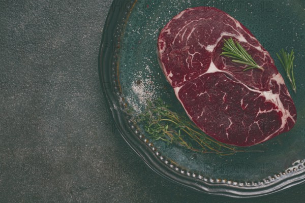 Steak made from fresh beef, with herbs and various spices, on a plate, ready to cook, there are no people