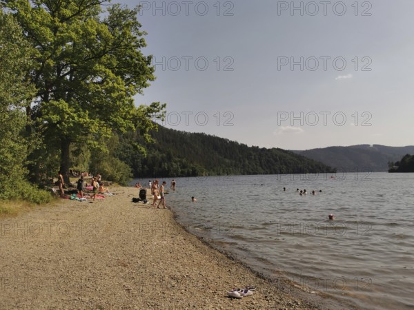 Bathers relax on a pebble beach on a quiet lake, Hohenwarte Reservoir, Thuringian Forest nature park Park