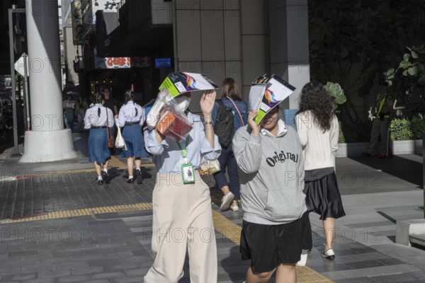 Bangkok, Thailand. March 25th 2025. People shield their faces from the bright sun and wear face masks during the intense summer heat in the Thai capital, Bangkok, Thailand