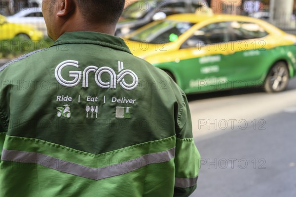 Bangkok, Thailand. March 25th 2025. Ride, Eat, Deliver, the Grab food delivery service logo displayed on the shirt of a Grab delivery rider in Bangkok, Thailand, Asia