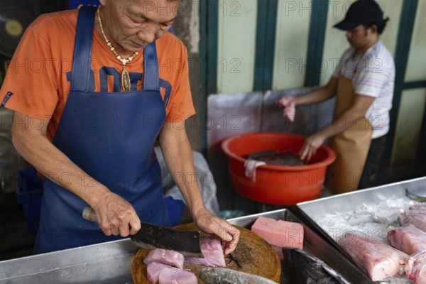 Bangkok, Thailand. March 10th 2025 A fishmonger chops tuna steaks in street market stall in Chinatown, Bangkok Thailand
