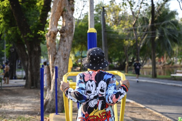 Bangkok, Thailand. March 4th 2025. An elderly lady uses the public outdoor gym exercise machines in Lumphini Park, Bangkok