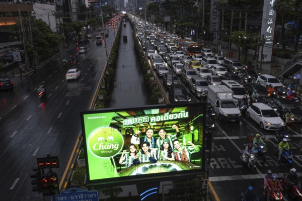 Bangkok, Thailand. March 26th 2025. An illuminated advertisement for Chang Beer in the busy downtown Sathon business district during the evening rush hour, Bangkok, Thailand