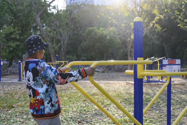 Bangkok, Thailand. March 4th 2025. An elderly lady uses the public outdoor gym exercise machines in Lumphini Park, Bangkok, Thailand