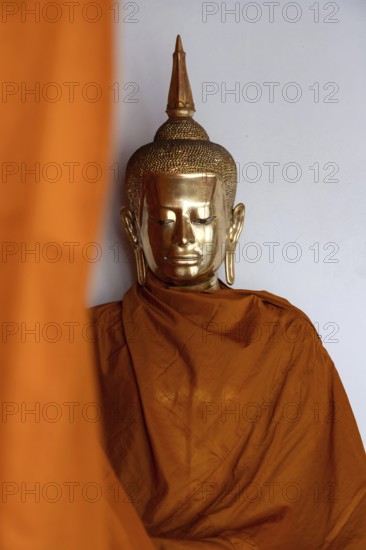 A golden Buddha image covered in orange cloth in preparation for cleaning at Wat Pho Temple complex known for The Reclining Buddha, Bangkok, Thailand