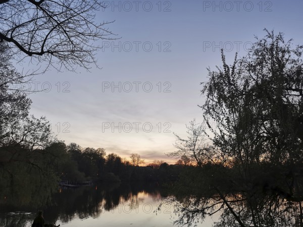 The sunset is reflected in a lake surrounded by trees, Franconian Forest nature park Park
