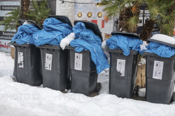 Overfilled garbage cans in the snow for collection, pedestrian zone, Nuremberg, Middle Franconia, Bavaria, Germany