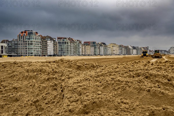 Bulldozers when distributing sand on the beach in the town of Knokke-Heist, part of coastal protection and beach maintenance, due to floods, erosion and sea level rise, the sand on the beach is repeatedly washed into the sea, in winter the sand from the seabed is washed back onto the beach with suction vessels, the excavators and levelers then distribute the sand back on the beach to eliminate the difference in height so as to bathe To make the beach usable again for the next season