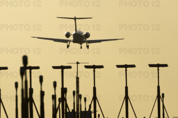 Cessna Citation small executive business jet aircraft in flight on approach to land over runway lights at sunset at London Stansted airport, Essex, England, United Kingdom