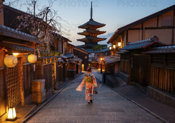 Japanese woman wearing kimono in an alley, Yasaka dori historic alleyway in the old town with traditional Japanese houses, five-story Yasaka pagoda of the Buddhist Hokanji Temple in the back, Higashiyama, Kyoto, Japan