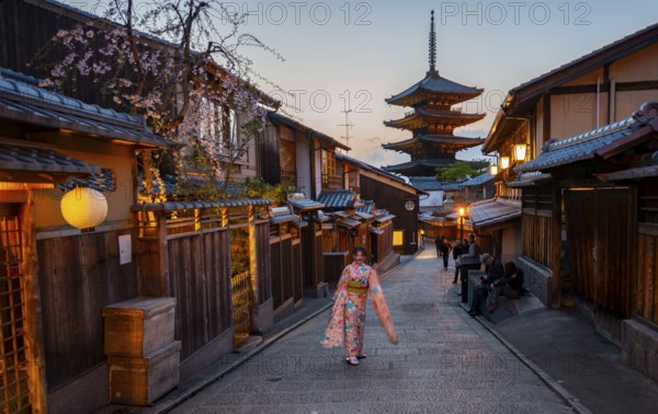Japanese woman in kimono in an alley, Yasaka dori historic alleyway in the old town with traditional Japanese houses, five-story Yasaka pagoda of the Buddhist Hokanji temple, evening mood, Kyoto, Japan