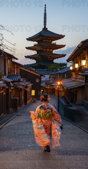 Japanese woman wearing kimono in an alley, Yasaka dori historic alleyway in the old town with traditional Japanese houses, five-story Yasaka pagoda of the Buddhist Hokanji Temple in the back, Higashiyama, Kyoto, Japan