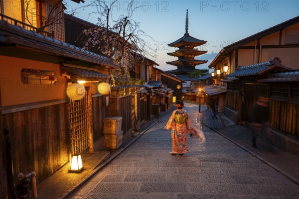 Japanese woman in kimono in an alley, Yasaka dori historic alleyway in the old town with traditional Japanese houses, five-story Yasaka Pagoda of the Buddhist Hokanji Temple in the back, evening mood, blue hour, Higashiyama, Kyoto, Japan