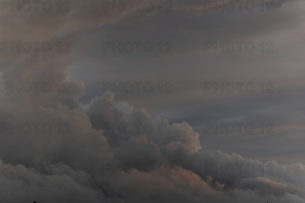 Clouds form in the sky. It is late in the day. The clouds are thick and grey. The sky shows various shades