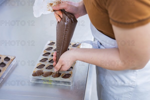 Hand fills chocolate in chocolate form, craftsmanship and precision, vegan chocolates production, Haselstaller Hof, Gechingen, Germany
