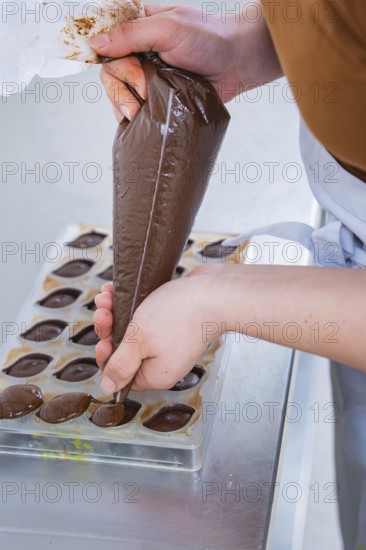 Hand fills chocolate in chocolate form, careful preparation, vegan chocolates production, Haselstaller Hof, Gechingen, Germany