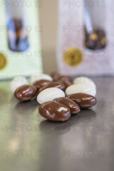 Close-up of white and brown chocolate almonds with packaging in the background, Easter production of regional products, Haselstaller Hof, Gechingen, Calw district, Germany