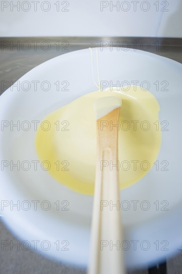 White chocolate on a spoon in liquid state, Easter production of regional products, Haselstaller Hof, Gechingen, Calw district, Germany