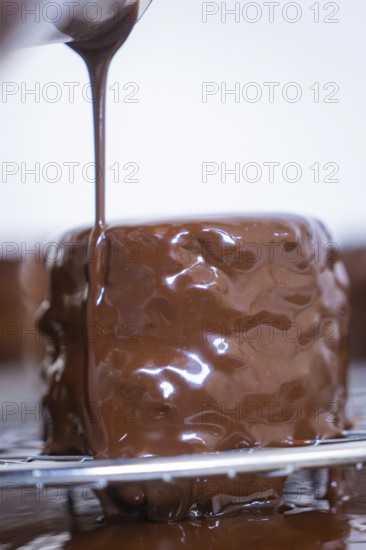 Close-up of a cake being poured over with liquid chocolate, Vegan Tart Production, Haselstaller Hof, Gechingen, Germany
