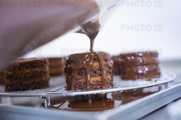 Liquid chocolate is poured over a cake on a grid in a kitchen, Vegan Tart Production, Haselstaller Hof, Gechingen, Germany