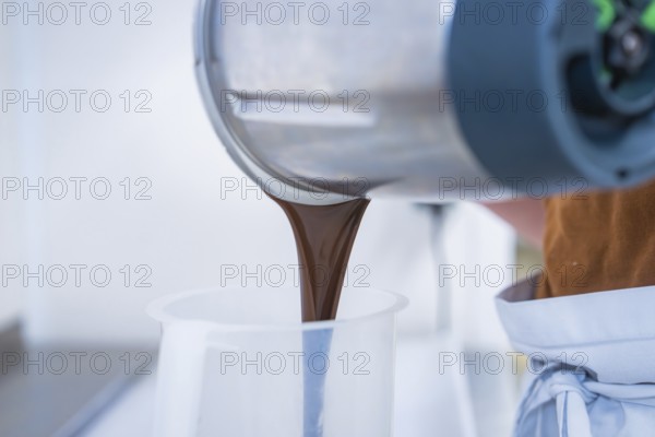 Liquid chocolate is poured from a mixer, Vegan Tarts Production, Haselstaller Hof, Gechingen, Germany