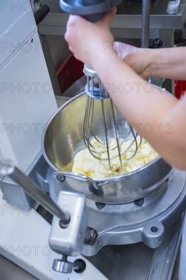 A person uses a mixer in a silver bowl to mix ingredients, vegan cake production, Haselstaller Hof, Gechingen, Germany
