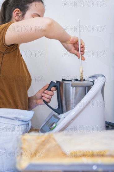 Woman stirring ingredients in a mixer in the kitchen, vegan cake production, Haselstaller Hof, Gechingen, Germany